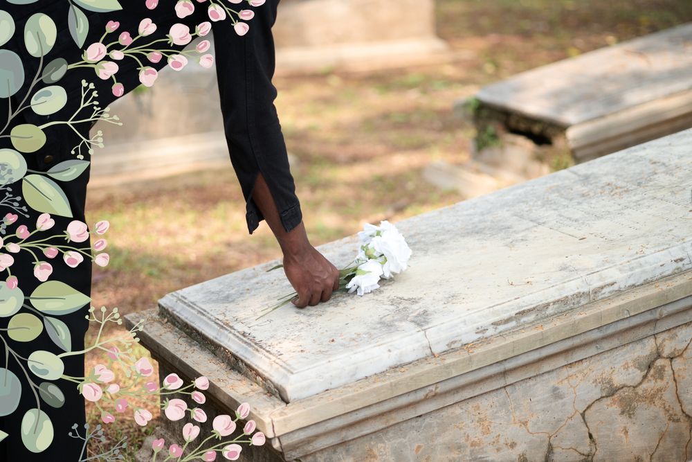 A hand gently laying white flowers on a memorial stone